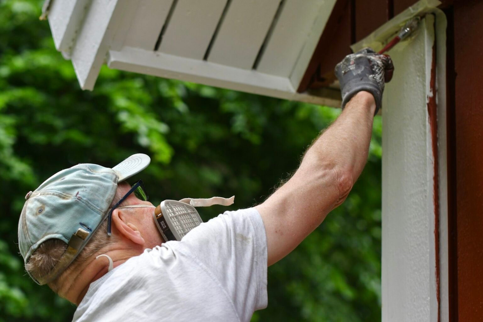 Homme peignant l'extérieur d'une maison.