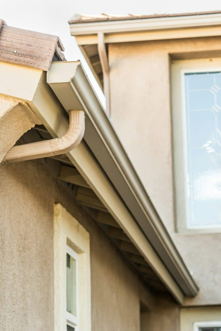 Gouttière installée le long du toit d'une maison beige.