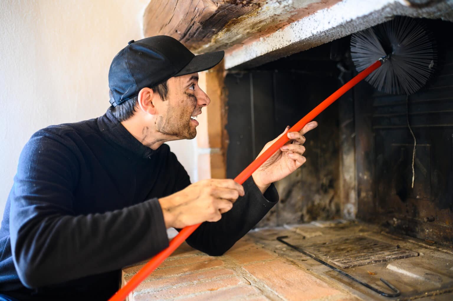 Ramoneur entrain de faire un ramonage d'une cheminée avec une brosse.